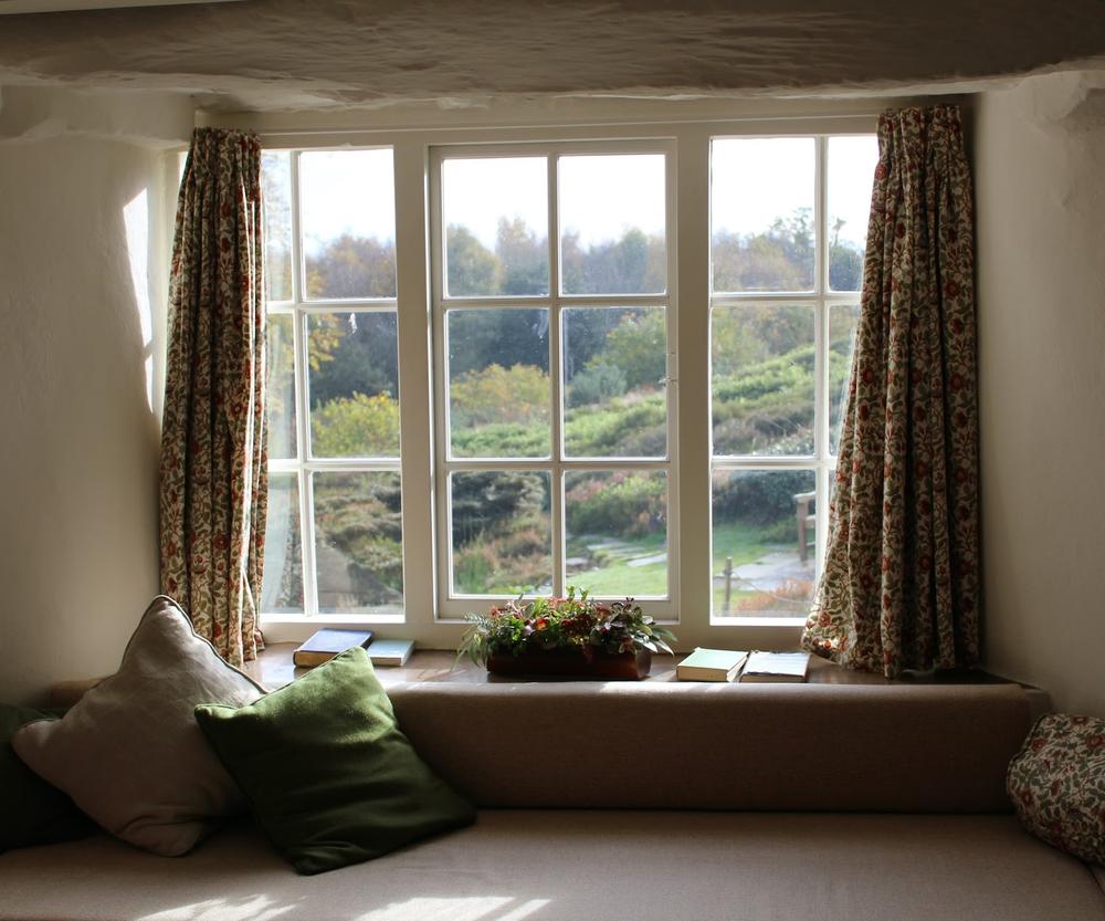 bow window avec des coussins et des livres avec vue sur la campagne