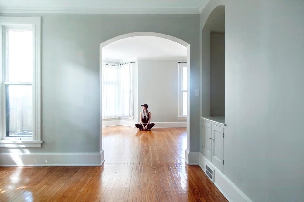 une jeune femme assise au sol d'un appartement vide