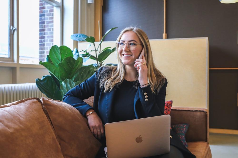 une femme en tailleur au telephone sur un canapé