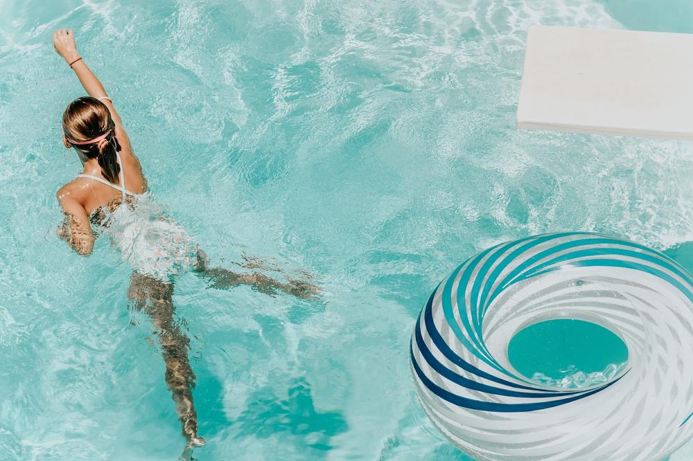 une femme qui nage dans une pisicne avec une  bouet bleue à côté
